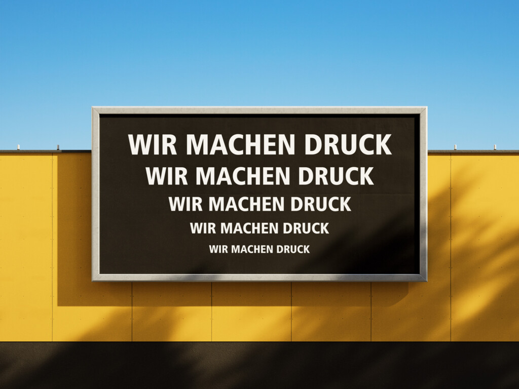 Ein schwarzes Schild, darauf in weißen Versalien WIR MACHEN DRUCK in fünf Schriftgrößen