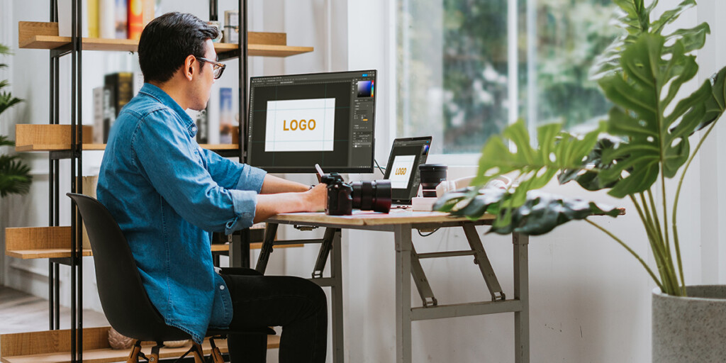Person sitzt am Schreibtisch und erstellt Druckdaten mit einem professionellem Layout-Programm.
