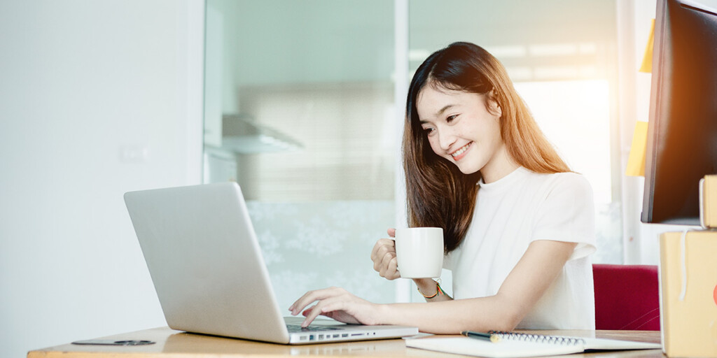 Frau sitzt vor ihrem Laptop und erstellt Druckdaten.