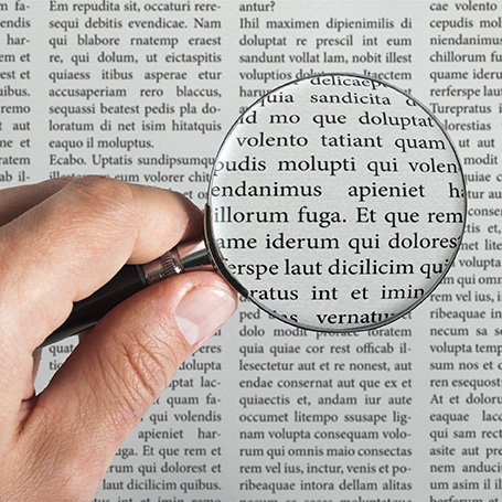 Lupe auf Zeitungstext verdeutlicht die Mindestschriftgröße, um gut lesbare Druckdaten zu erstellen.