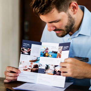 Flyer mit Wickelfalz, eine der aufklappbaren Falzarten, in den Händen eines Rezeptionisten