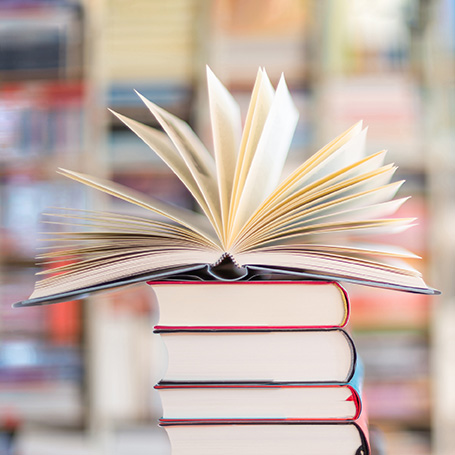 Durch Selfpublishing im Buchhandel: vier gestapelte Bücher mit einem breit aufgefächerten darauf