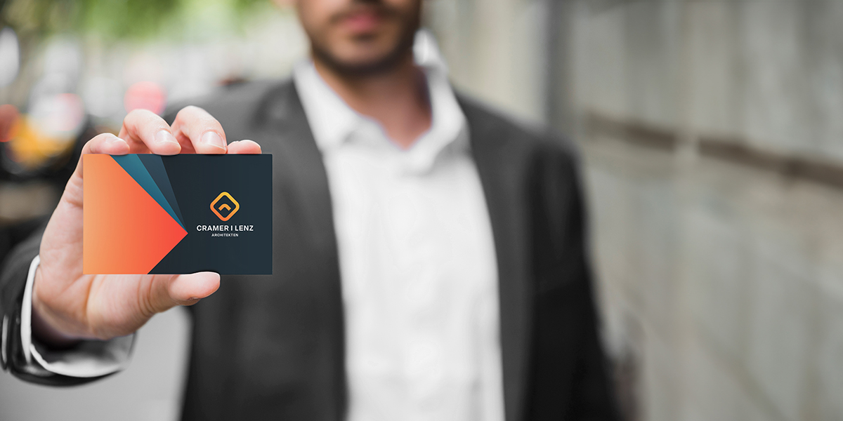 Mann hält Business Card in der standardisierten Visitenkartengröße in die Kamera.