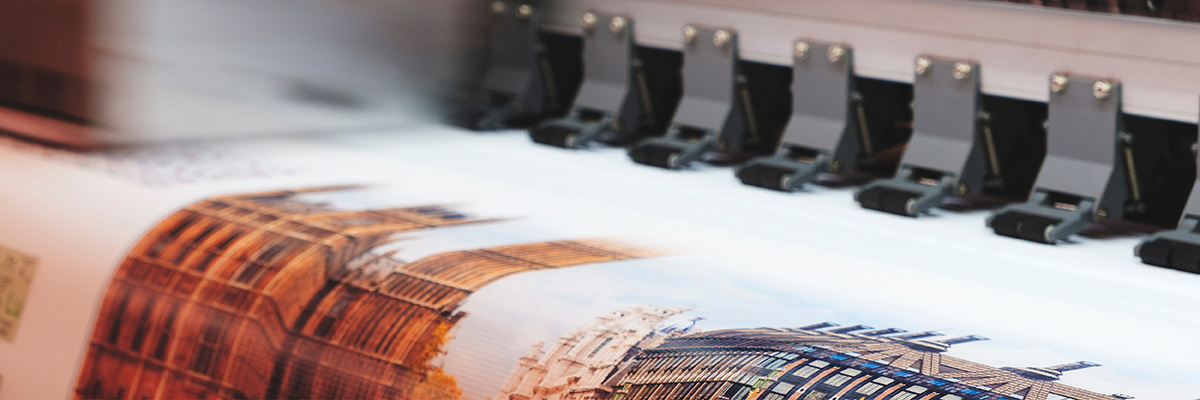 Druckproduktion 2026: Nahaufnahme industrieller Inkjetdrucker beim Drucken eines Motivs mit Gebäuden