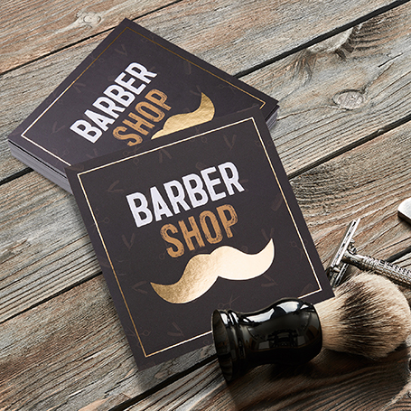 Ein Stapel Flyer mit der Aufschrift "BARBER SHOP" & einem Bart-Icon auf einem Tisch
