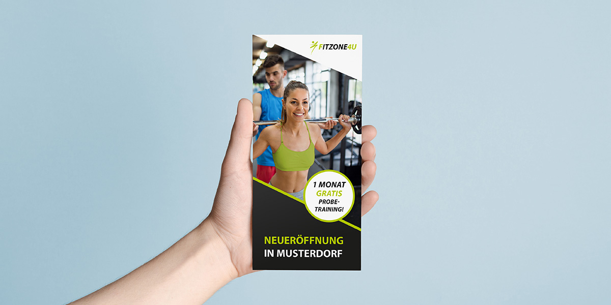 Eine Hand hält einen Flyer eines Fitnessstudios als Beispiel für einen Flyer-Aufbau