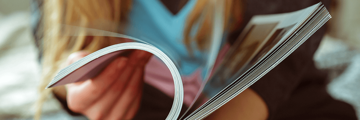 Onlinedruckliebe: eine Person in blauem Pullover mit langen blonden Haaren blättert in Magazin