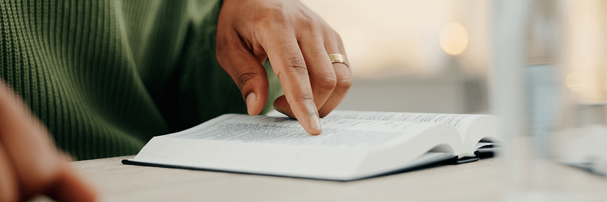 Onlinedruckliebe: eine Person mit Ring in grünem Pullover liest mit dem Finger ein Buch