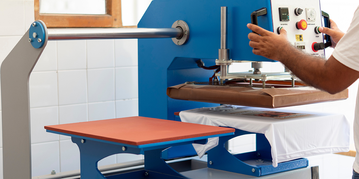 Person beim T-Shirt-Bedrucken mittels Sublimationsdruck mit Textil-Transferpresse