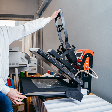 Person bedient Transferpresse für Digitaltransferdruck, einem T-Shirt-Druckverfahren