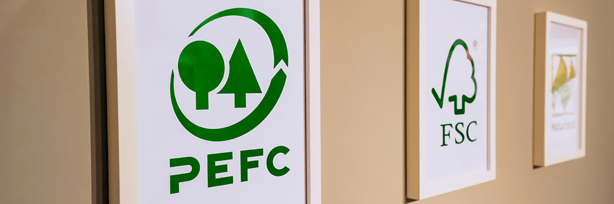 Eine Wand mit Bilderrahmen, in denen die Siegel-Logos von PEFC, FSC usw. zu sehen sind