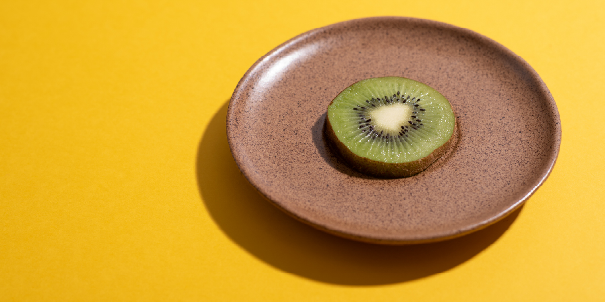 Farbkontrast Quantitätskontrast: grüne Kiwi-Scheibe auf braunem Teller auf orangefarbenem Hintergrund