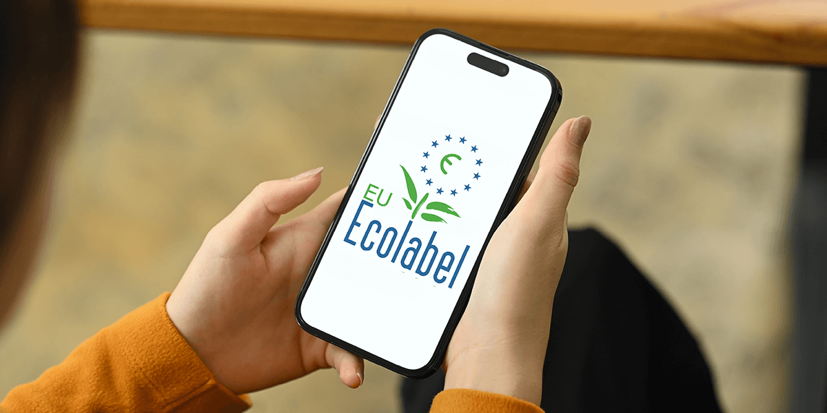 Person mit Handy, dessen Display das Logo des Umweltsiegels EU-Ecolabel zeigt