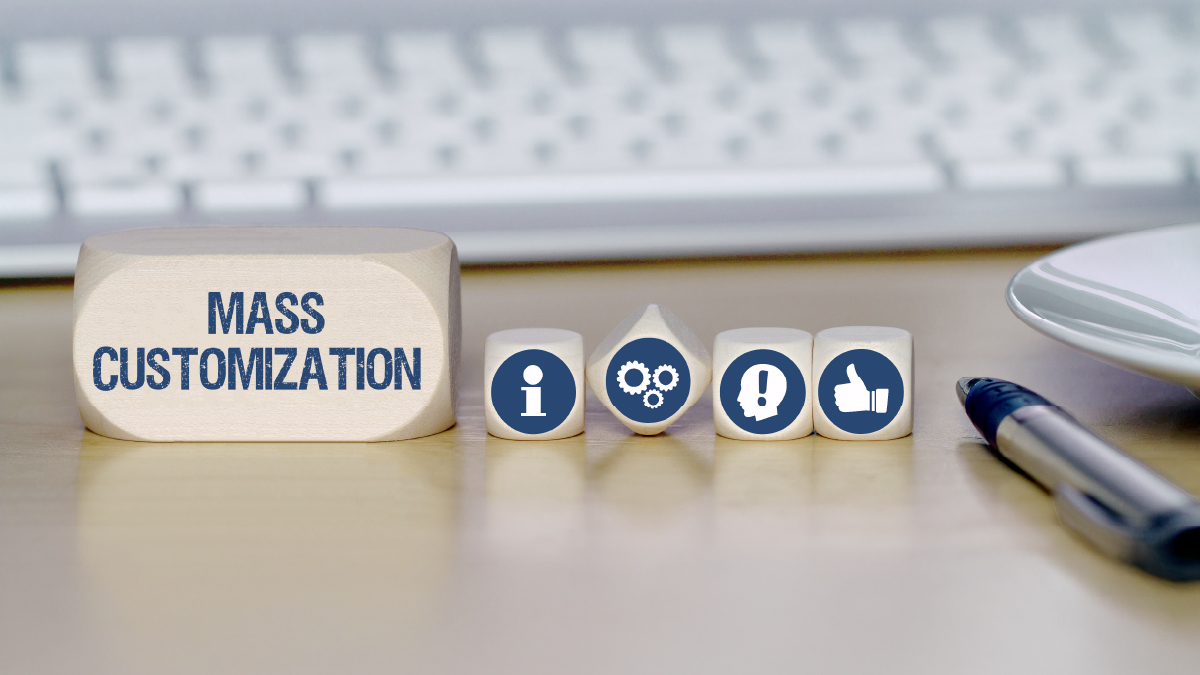 Würfel auf Schreibtisch mit Aufschrift "MASS CUSTOMIZATION" & Icons wie Info-i, Zahnräder & Daumen hoch