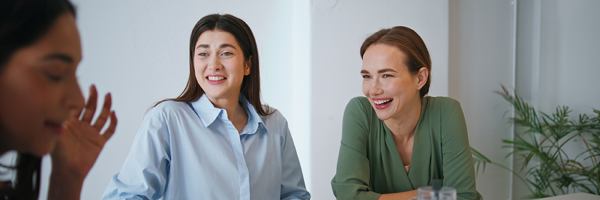 Drei Frauen lächeln beim Planen einer Hochzeitszeitung