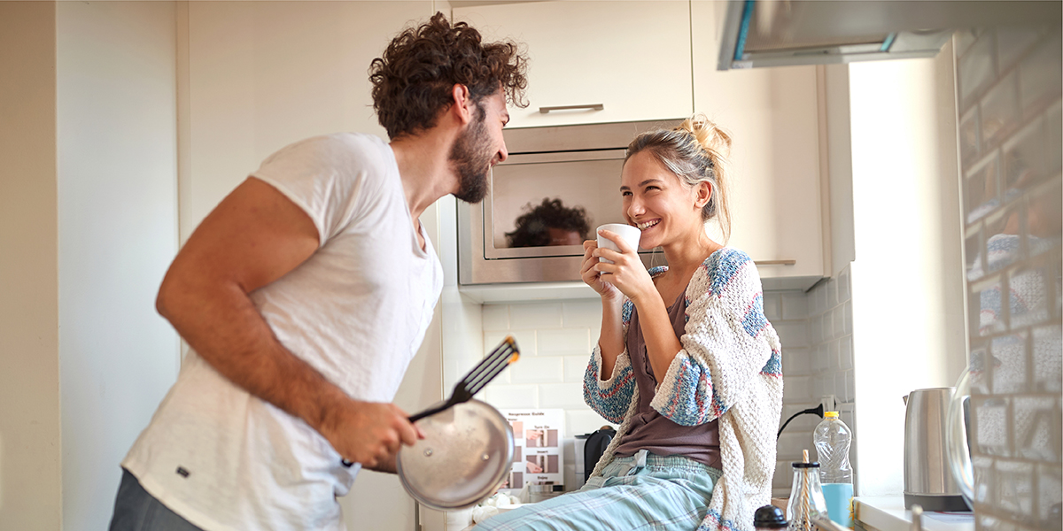 Ein Paar (Frau & Mann) beim Kochen in der Küche, beide lachen