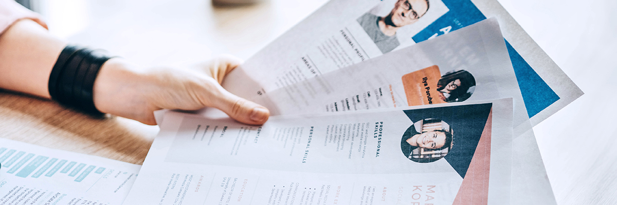 Personaler betrachtet verschiedene Lebensläufe mit Fotos und in bunten Designs