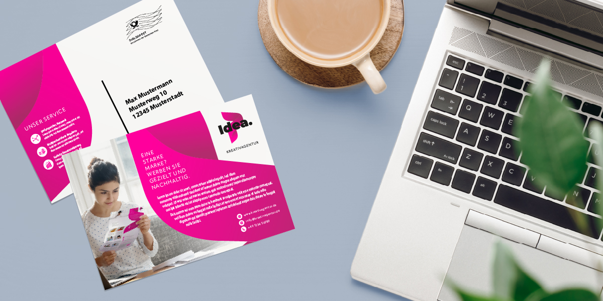 Beispiel für ein Post-Mailing: ein Postkarten-Mailing in pinkem Design neben Kaffeetasse und Laptop