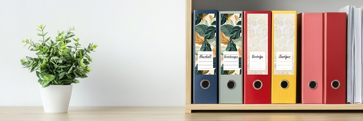 Regal mit grüner Pflanzte steht & bunten Ordnern, auf denen bunte Etiketten mit Beschriftungen kleben