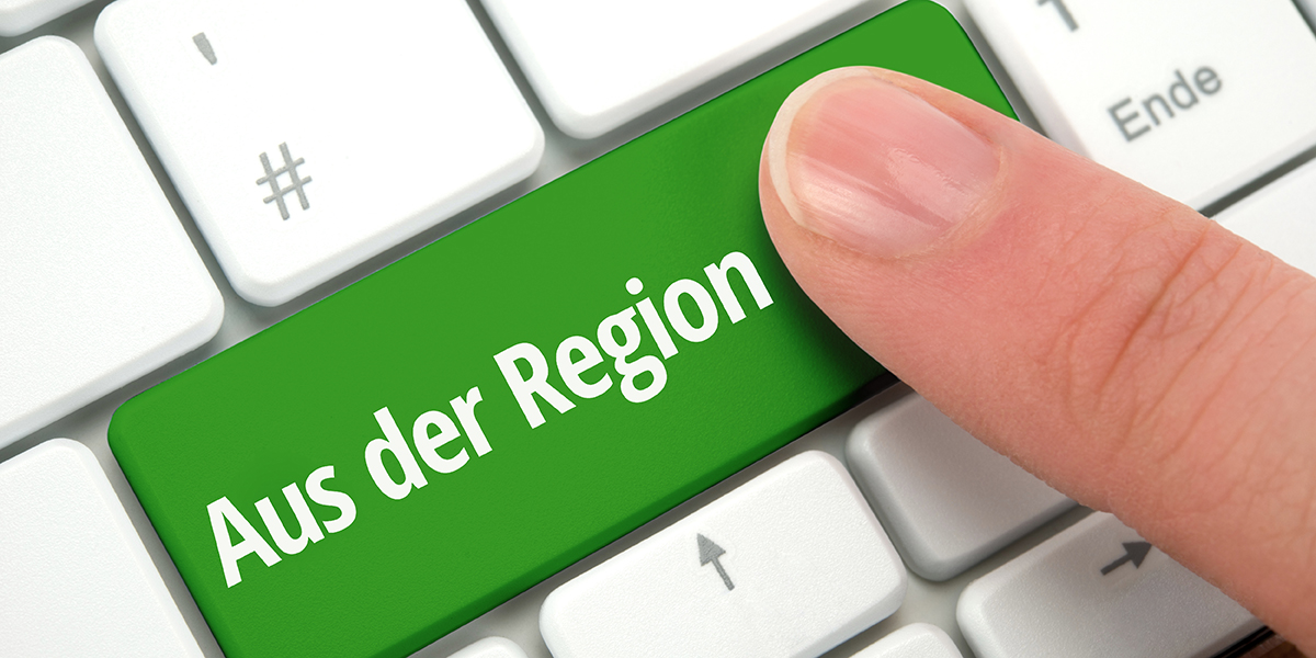 Ein Finger drückt auf einer weißen Tastatur eine grüne Taste mit der Aufschrift: "Aus der Region"