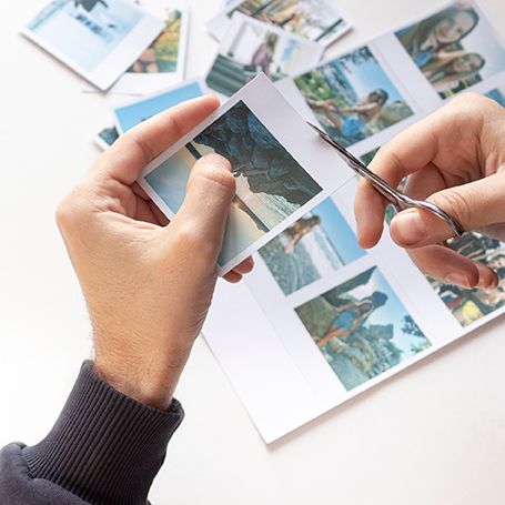 Zwei Hände schneiden Urlaubsfotos aus, um eine Collage für eine Hochzeitszeitung zu machen