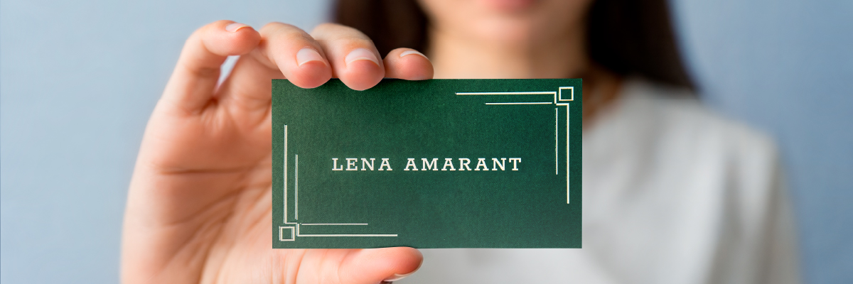 Visitenkartenidee: Hand hält grüne Visitenkarte hoch mit cremefarbener Schrift und Elementen