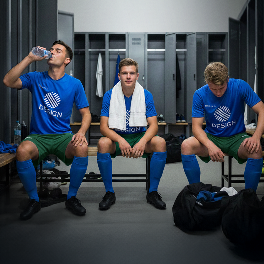 Drei Männer in einer Umkleide tragen einen Craft-Trikotsatz mit individuellem Design in Blau & Grün