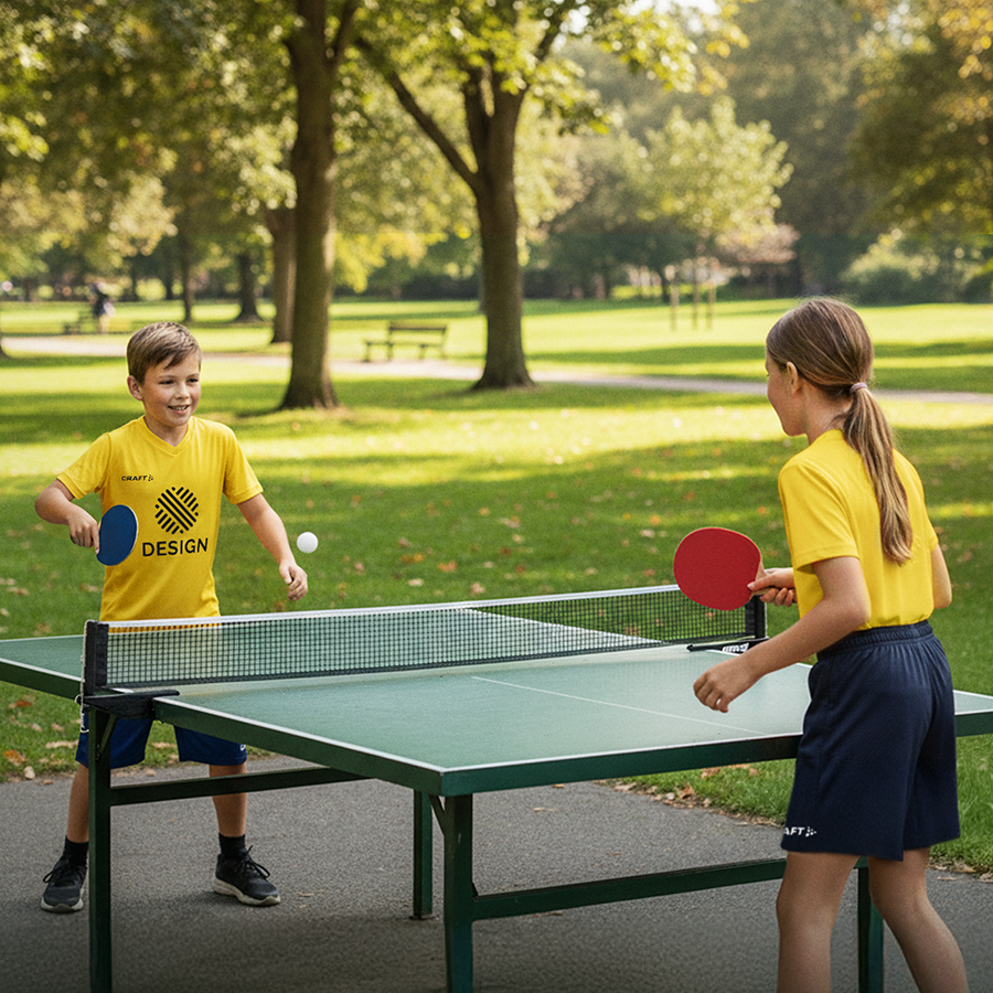 Zwei Kinder mit bedruckten Craft-Trikotsets spielen Tischtennis