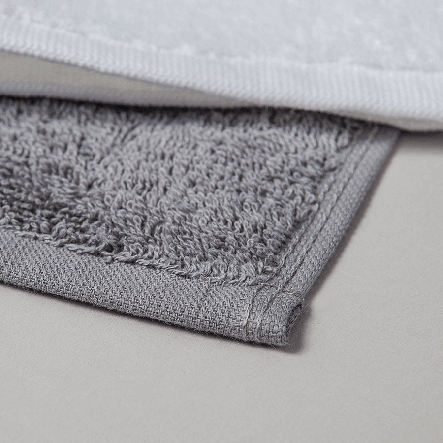 Detailaufnahme von zwei Handtüchern in weiß und grau, aus saugfähigem Walkfrottier