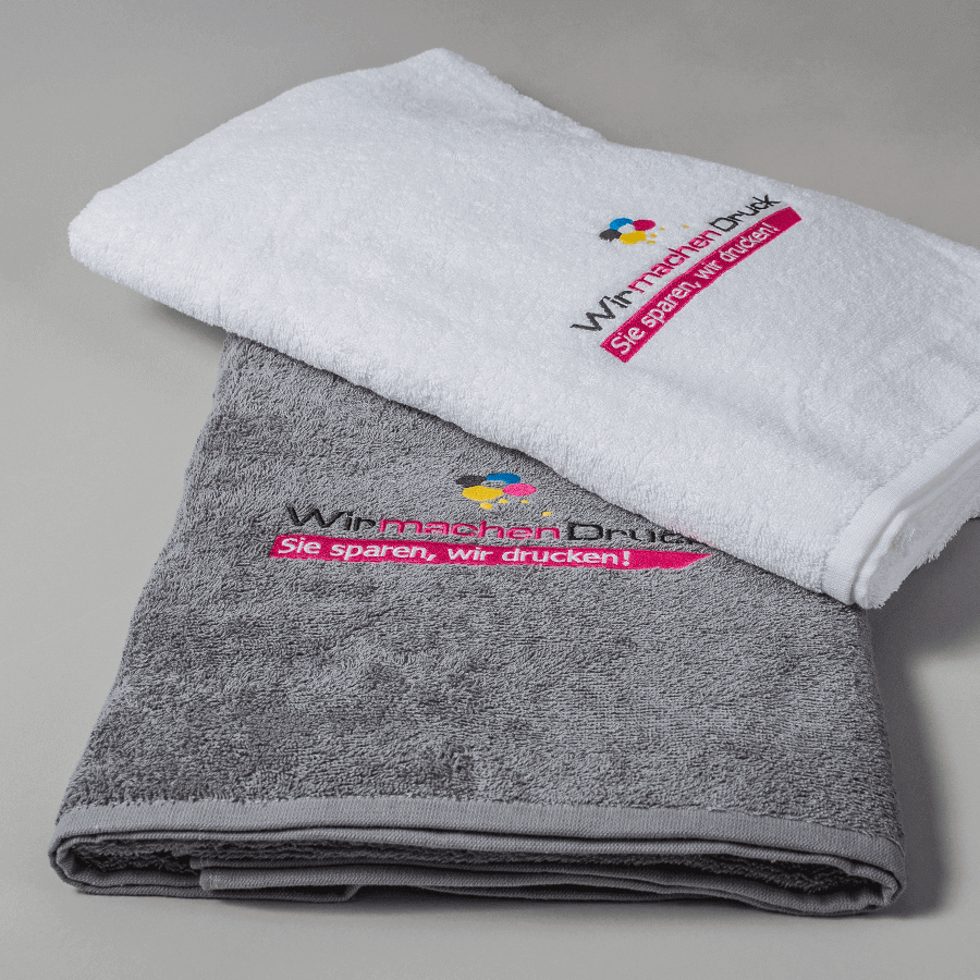 Gestapelte Handtücher in weiß und grau, individuell mit Wunschmotiv bestickt