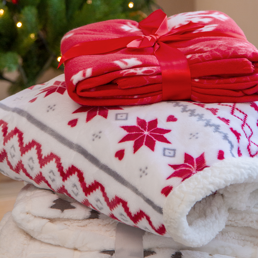 Ein Stapel kuschelige Weihnachts-Fleecedecken mit verschiedenen Motiven