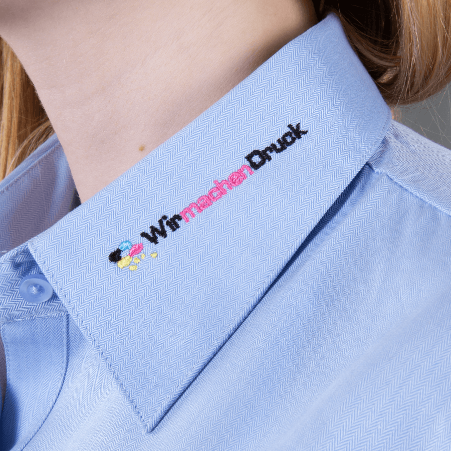 Detailansicht einer hellblauen Bluse mit individueller Stickerei am Kragen