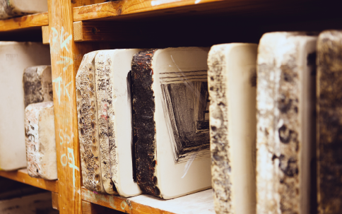 Mehrere bemalte Steinplatten (Lithografiesteine) für Lithografieverfahren nebeneinander in Regal angeordnet