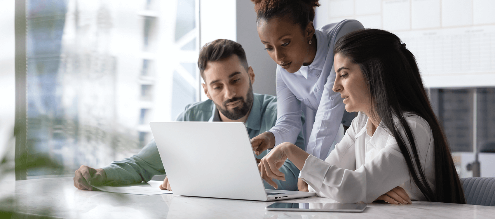 Drei Personen in einem hellen Büro gucken konzentriert auf einem Laptop ihren Closed Shop an