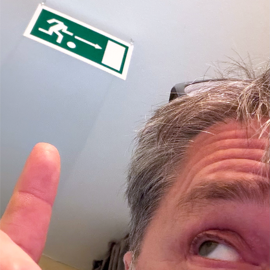 Einsendung WIRmachenFANS-Gewinnspiel: Mann zeigt auf Notausgang-Schild