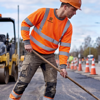 Ein Mann mit bedrucktem Warnschutz-Sweatshirt arbeitet im Straßenbau