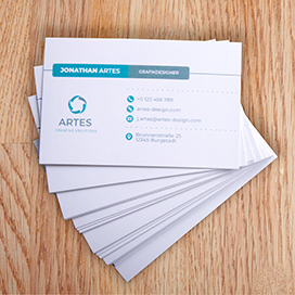 Aufgefächerte gedruckte Visitenkarten auf einem hellbraunen Tisch